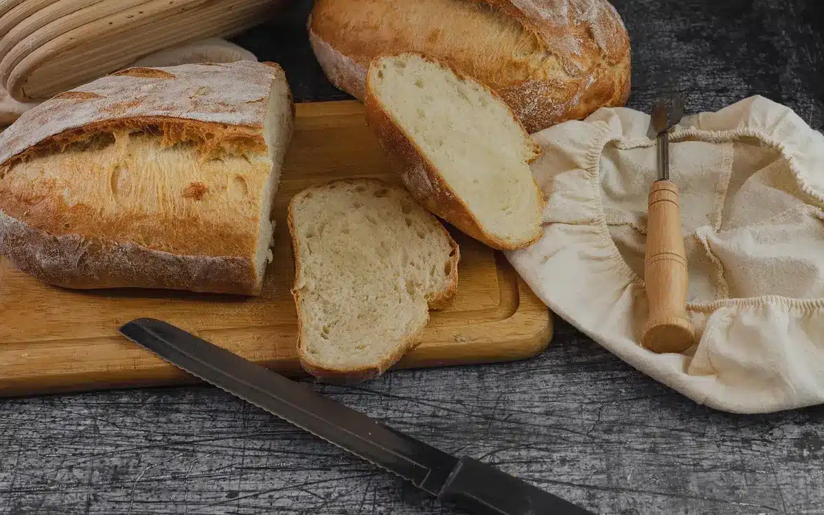 Hand snijdt beschimmeld brood weg op een snijplank