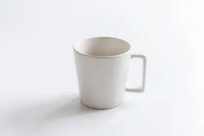 Anonieme persoon bij keukentafel met pillendoosje, kopje thee en medische folder