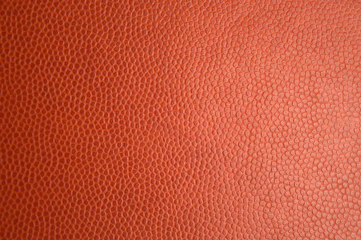 Close-up van oranjebloesem naast leerachtige textuur en parfumfles