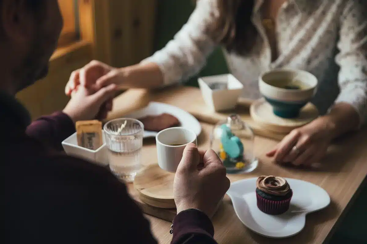 Handen bladeren door vintage modetijdschriften op een houten tafel met foto's en koffie