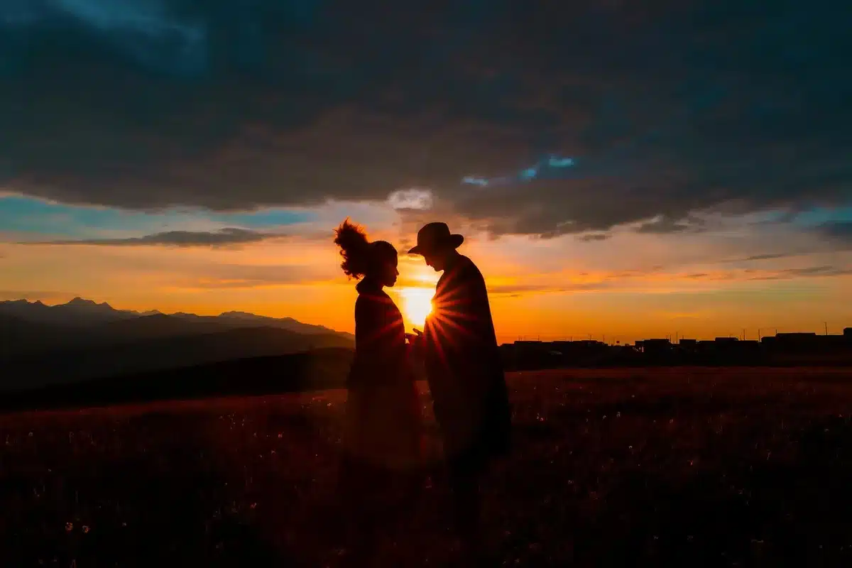 Zonsondergang boven een ranch en twee silhouetten die elkaar aankijken