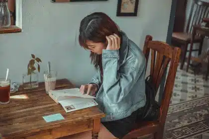Handen bij een open reisgids en instapkaartjes op een cafétafel in de stad