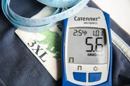 Anonieme handen meten buikomtrek met meetlint op een neutrale kliniektabel