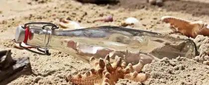 Handen sprayen twee parfumflesjes boven sjaal en handschoenen op houten tafel