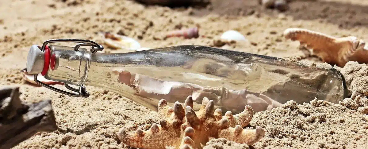 Handen sprayen twee parfumflesjes boven sjaal en handschoenen op houten tafel